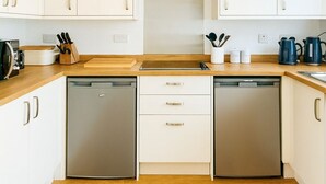 A compact kitchen with white cabinets, two dishwashers, a central stove hood, and a brown patterned rug.