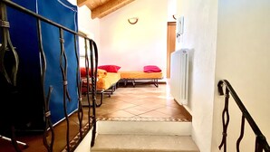 Una escalera conduce a un dormitorio con dos camas, un radiador y un techo de madera.