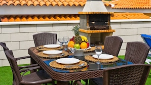 An outdoor dining area with wicker chairs, a glass table, and a stone barbecue grill. - BEAUTIFUL HOLIDAY HOME 273 WITH PRIVATE POOL (Callao Salvaje)