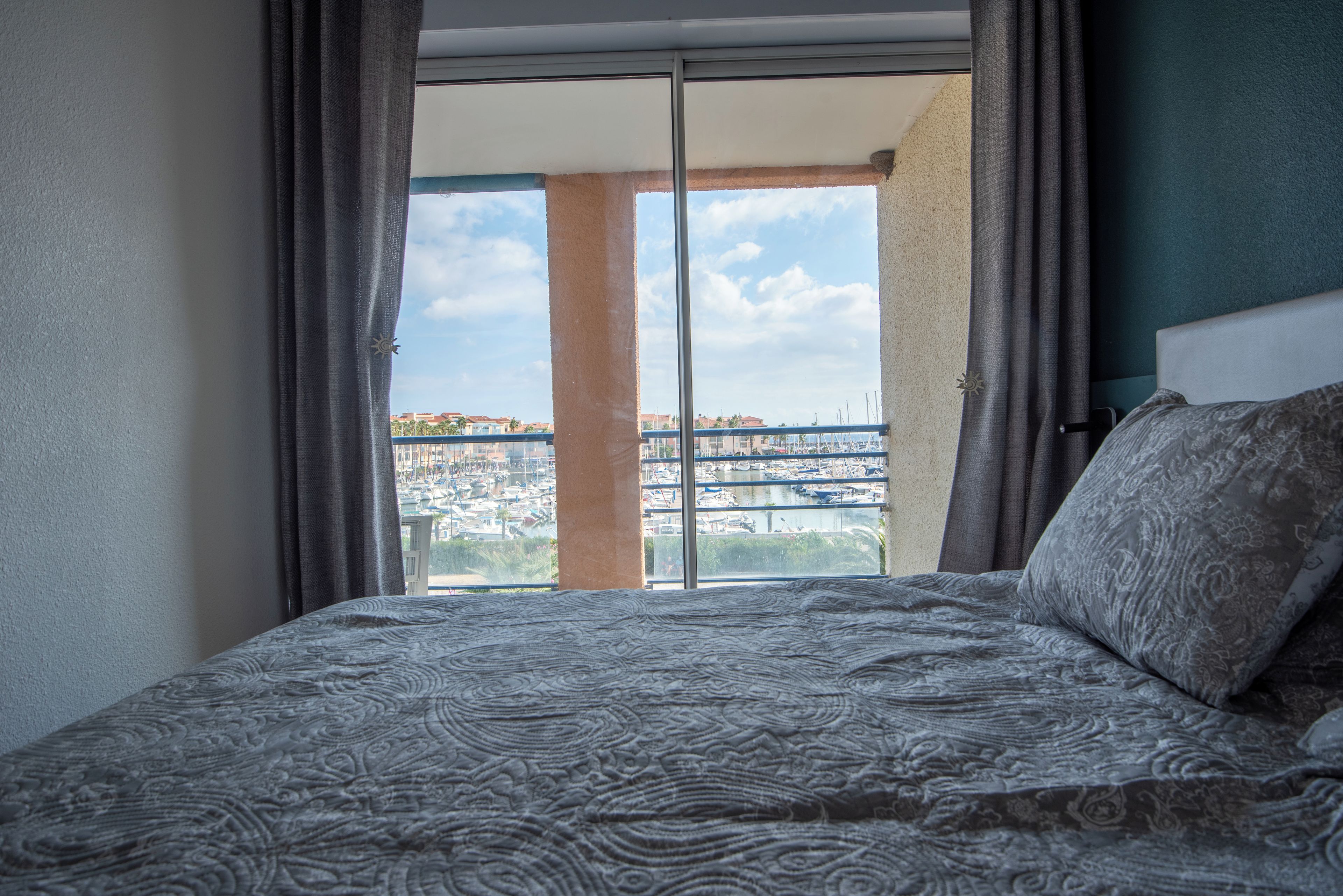 Ein Hotelzimmer mit einem großen Bett, Blick auf eine Marina und einem Balkon mit Stadtansicht.