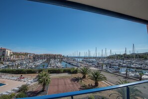 A marina with numerous boats docked, a clear sky, and a view of buildings in the background. - Superb T2 (sleeps 4-6) sea and Port Argeles in residence with pool (Argelès-Sur-Mer)