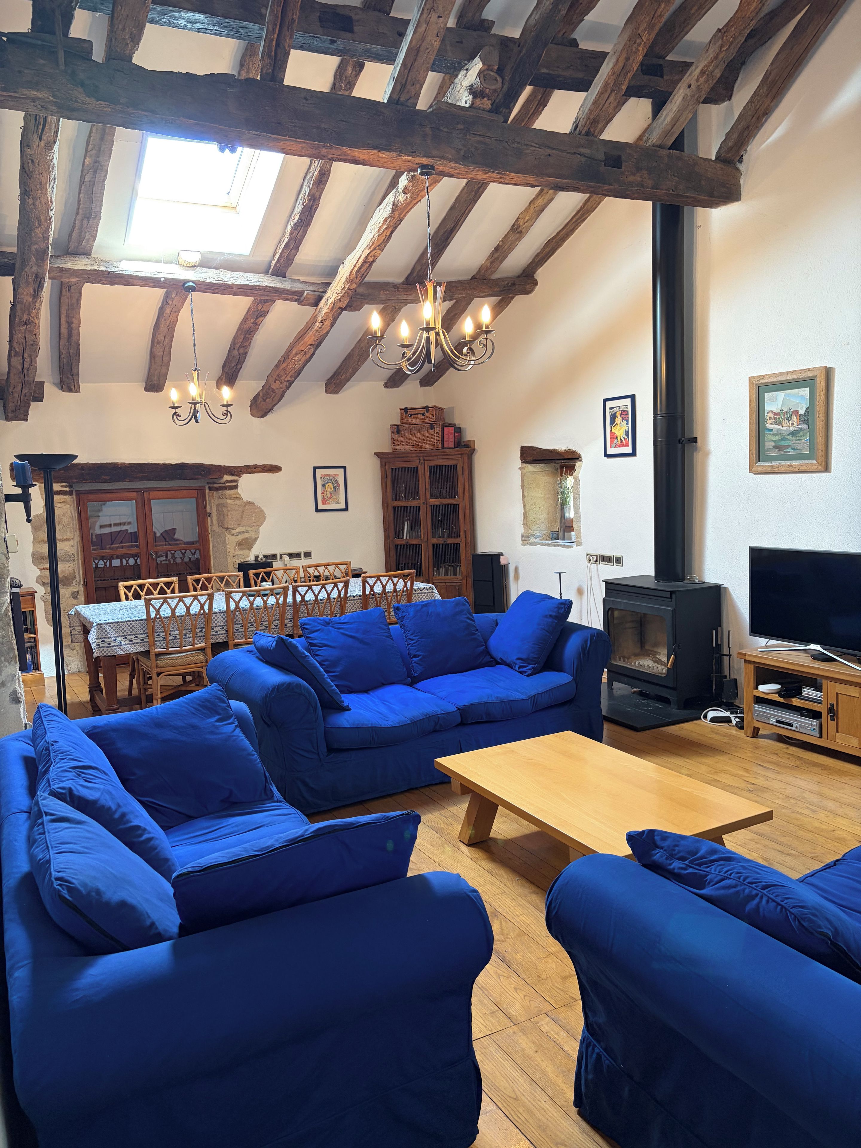 Ein Wohnzimmer mit Holzbalkendecke, einer Sofagarnitur, einem Fernseher und einem Kamin.