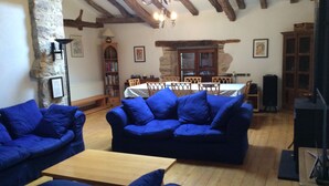 Una sala rústica con vigas de madera a la vista, pared de piedra y un comedor con muebles de madera.