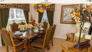 Comedor con una mesa de madera dispuesta para cuatro personas, rodeado de sillas tapizadas.