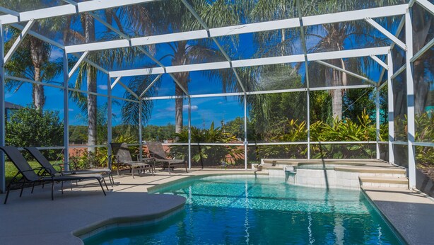 Un área de piscina con agua azul cristalina, rodeada por una estructura de pérgola blanca y equipada con sillones de descanso.