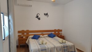 Een slaapkamer met een houten bed, twee nachtkastjes, een plafondventilator en een raam met gordijnen.