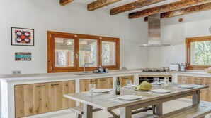 A modern kitchen with wooden cabinets, a central island, and a dining area with benches.