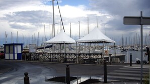 Un port esportiu amb diverses embarcacions amarrades, una zona d'estar coberta i un petit edifici blau.
