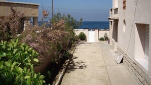 Un carrer estret amb vistes al mar, envoltat d'edificis amb murs de pedra i façana blanca.