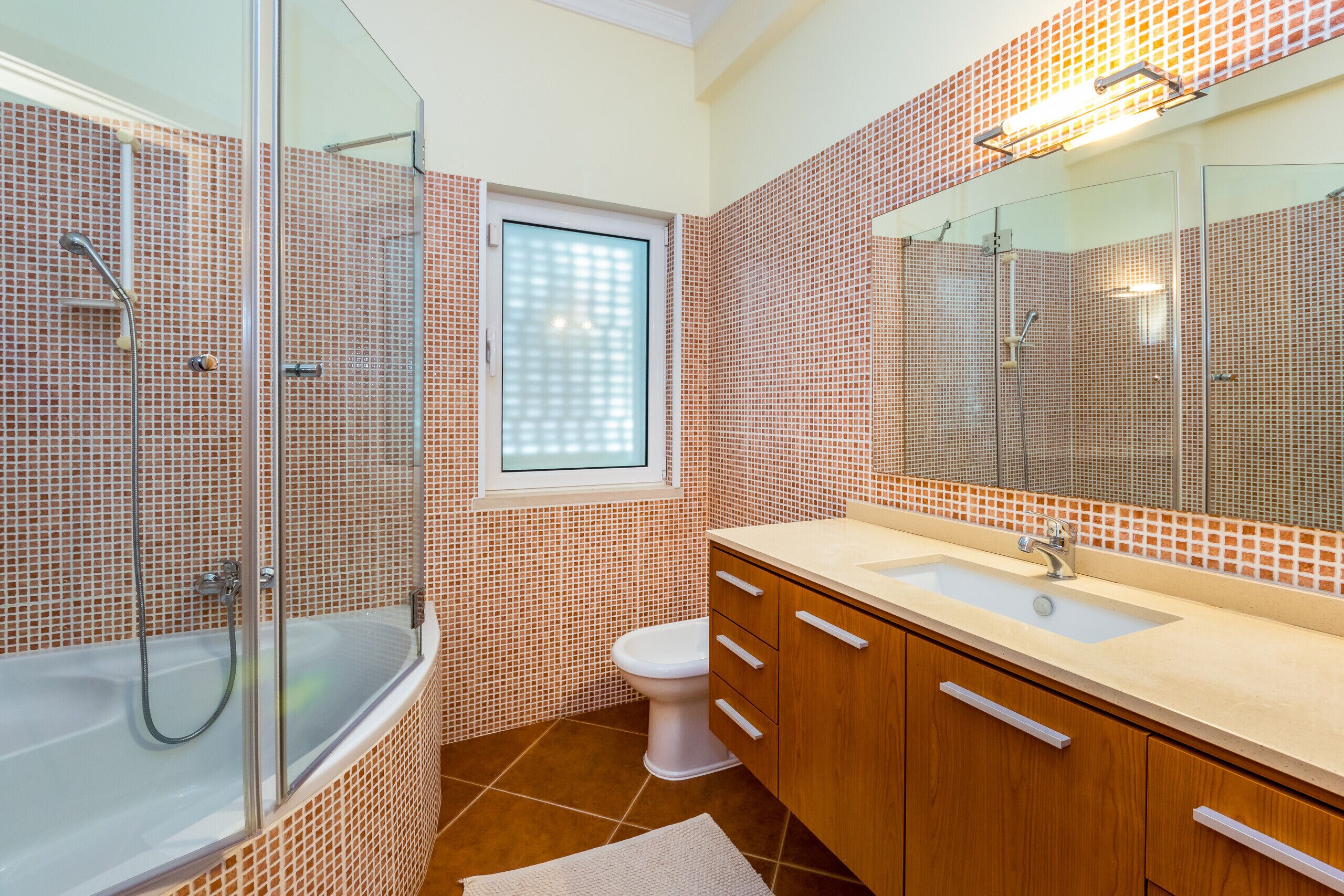A modern bathroom with a glass-enclosed shower, a white toilet, and wooden cabinets.