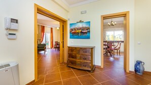 Un hall d’hôtel avec un meuble en bois, un tableau représentant un port et un téléphone fixé au mur.