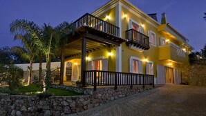 Une maison à deux étages avec un balcon, un mur en pierre et une allée pavée.