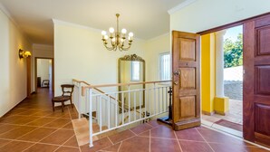 Un vaste hall d’entrée avec une porte en bois, un escalier et un lustre.