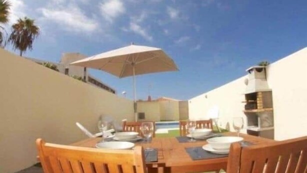 An outdoor dining area with a table set for two, a white umbrella, and a pool in the background. - FABULOUS DUPLEX C6 WITH PRIVATE POOL (Adeje)