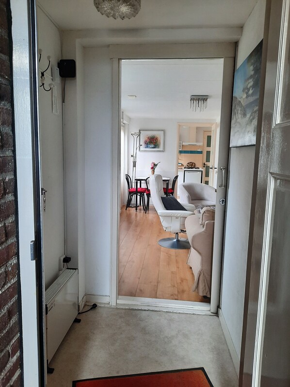 A doorway leading to a living room with a dining area, a sofa, and a radiator.