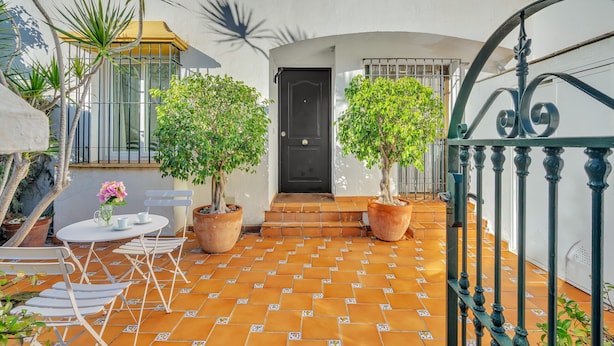 A courtyard with a tiled floor, a white door, and potted plants. - Casa Bella - Marbellamar (Marbella)