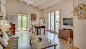 Un vaste salon doté d’un plafond en bois, un coin repas avec une table et des chaises, un canapé, une table basse et un téléviseur posé sur un meuble en bois.