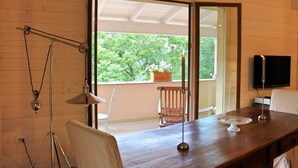 Une table de salle à manger en bois, avec une bougie, un téléviseur et une chaise.