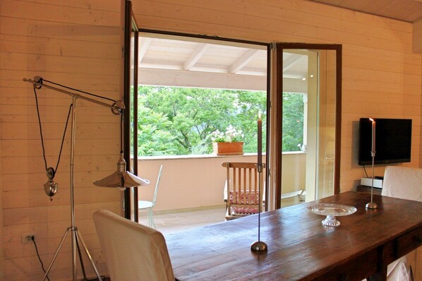 A wooden dining table with a candle, a television, and a chair. - Gorgeous loft with high ceilings, wooden interiors and panoramic terrace, pool (Spoleto)