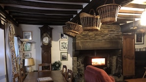 A cozy room with a long wooden table, red armchairs, a stone fireplace, and hanging baskets. - House / Villa - BERIGNY (Bérigny)