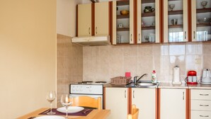 A compact kitchen with a stove, sink, and cabinets. There is a dining table with chairs and a wine glass. - A unit, One bedroom, stunning views, waterfront, free secured parking (Lipci)