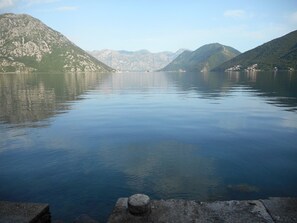 A calm lake with mountains in the background and a concrete structure in the foreground. - A unit, One bedroom, stunning views, waterfront, free secured parking (Lipci)