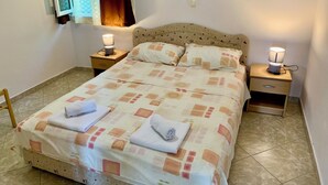 A neatly made bed with a patterned bedspread, two bedside lamps, and a window with curtains. - A unit, One bedroom, stunning views, waterfront, free secured parking (Lipci)