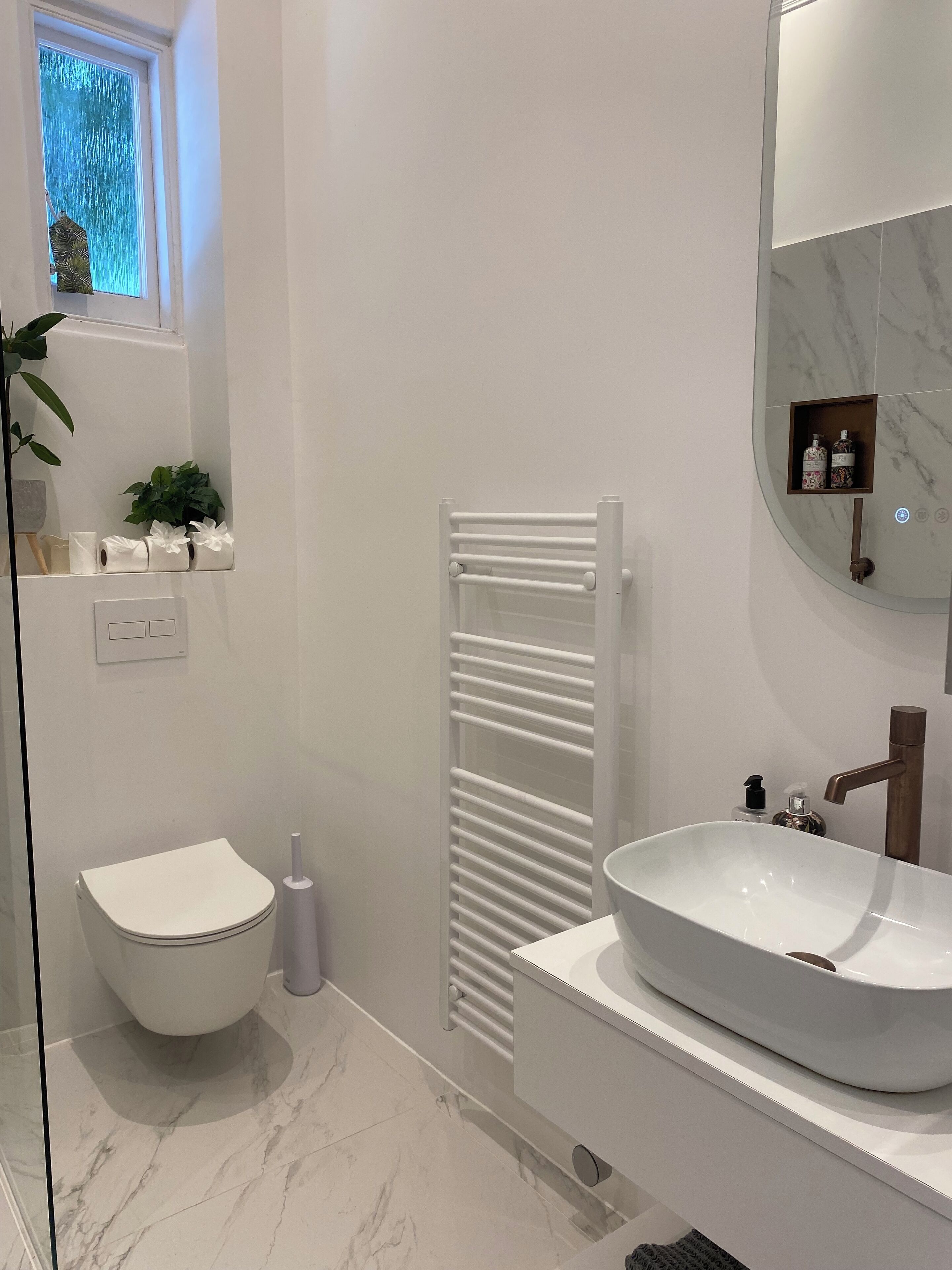 Uma casa de banho moderna com sanita branca, lavatório branco e um porta-toalhas.