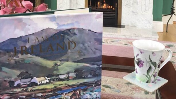 Une pièce avec une cheminée, un livre intitulé « Je suis l’Irlande », et une tasse à motifs floraux posée sur un dessous de verre.