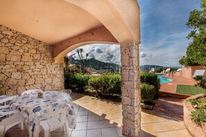 Eine überdachte Terrasse mit Steinmauern, einem Pool und Blick auf die Landschaft.