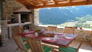 A rustic outdoor dining area with a stone fireplace, wooden ceiling, and a scenic mountain view. - Romantic-serene villa - heated swimming pool and superb view of the valley (Pengari)