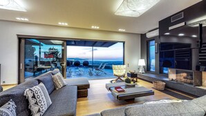 A modern living room with a large sliding glass door leading to an outdoor terrace with a city view.