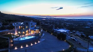 A modern villa with a swimming pool, multiple bedrooms, and a view of the surrounding landscape.