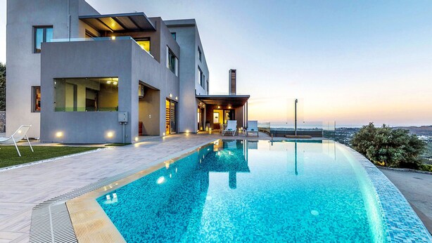 A modern house with a swimming pool, large windows, and a view of the landscape.