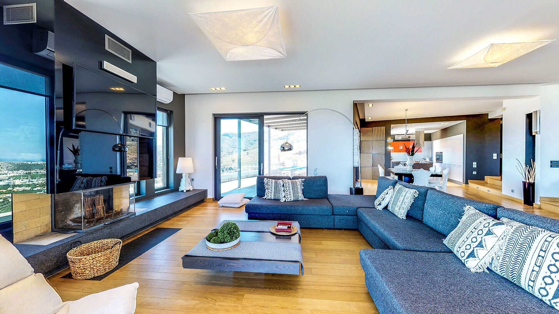 A spacious living room with a large sofa set, a coffee table with decorative items, and a view of the outdoors.