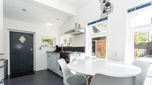 Una cocina moderna con armarios blancos, un refrigerador negro y un comedor con una mesa redonda y sillas blancas.
