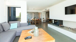 A modern living room with a grey sofa, a wooden coffee table, and a flat-screen TV mounted on the wall.