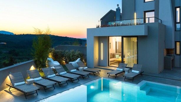 A modern house with a pool and lounge chairs.