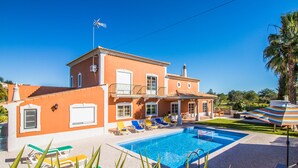 Een tweelaags huis met een zwembad, terras en een palmboom.
