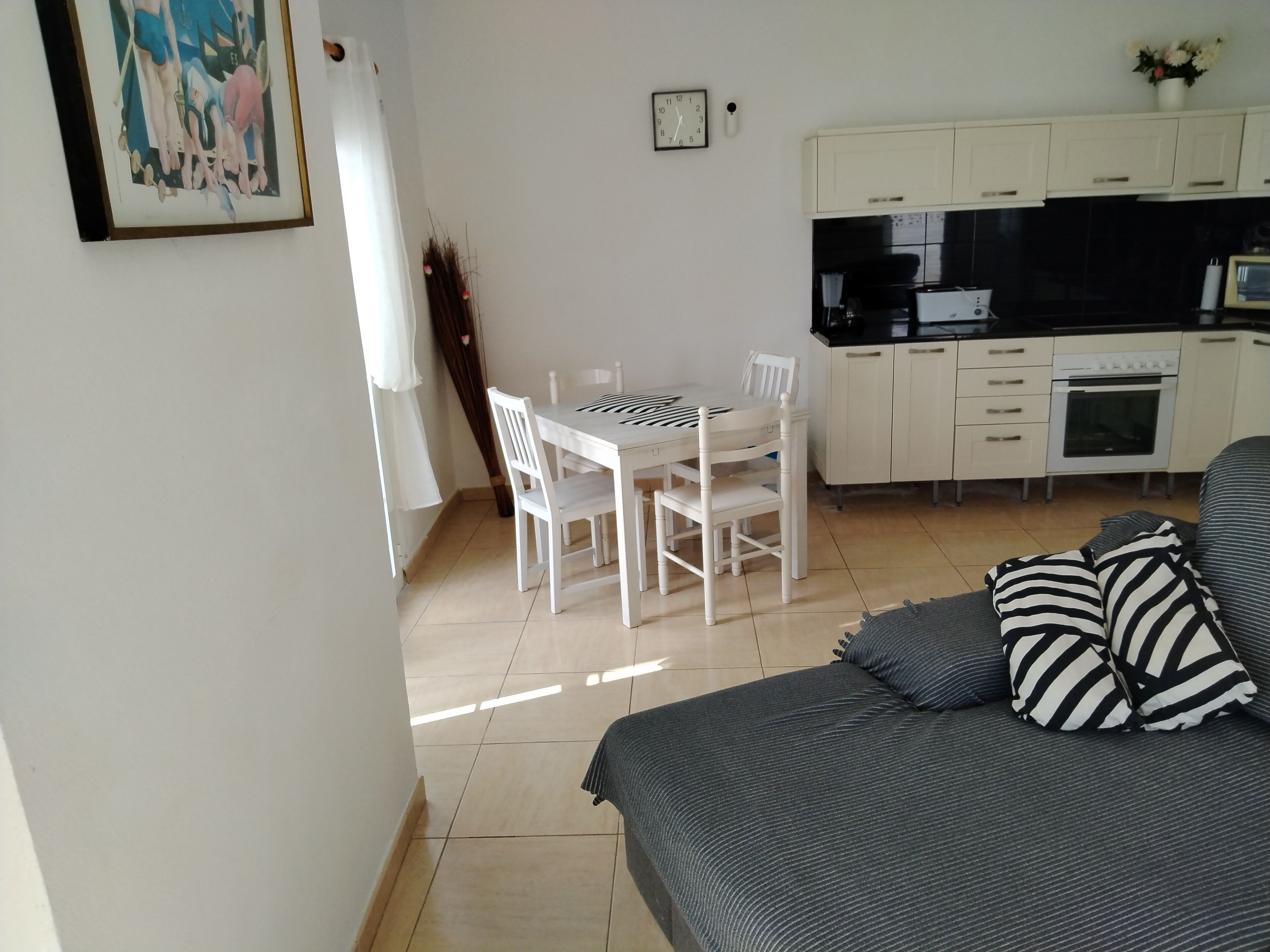 A compact living space with a dining area, kitchenette, and a sofa with striped pillows.