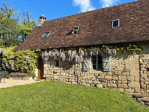 A stone building with a tiled roof, a small window, and a door. - Spacious farmhouse with private heated pool close to Collonges la Rouge (Meyssac)
