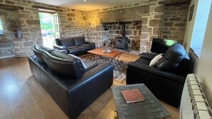 Ein Wohnzimmer mit Steinwänden, Ledersofas, einem Holztisch und einem Kamin.