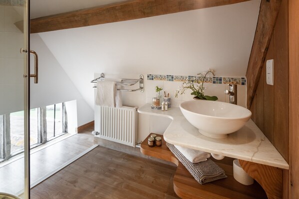 A modern bathroom with a large white basin, wooden accents, and a tiled backsplash. - Luxuriously renovated farmhouse with hot tub (Pylle)