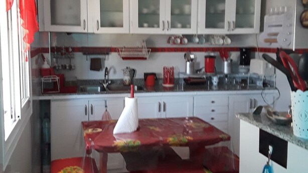 A kitchen with white cabinets, a red table, and a blue wall. - The pearl of Kouba lacroix   (kouba)