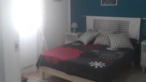 A bedroom with a bed, a nightstand, a lamp, a painting on the wall, and a window with curtains. - The pearl of Kouba lacroix   (kouba)