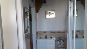 A narrow hallway with a white door on the left, a white cabinet with a sink, and a small potted plant on the floor. - The pearl of Kouba lacroix   (kouba)
