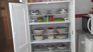 A kitchen with a built-in refrigerator, shelves with dishes, and a microwave. - The pearl of Kouba lacroix   (kouba)