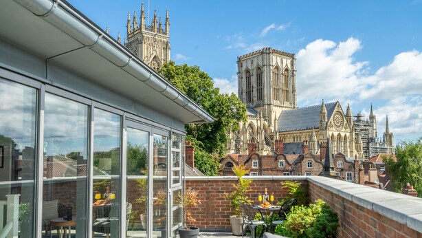 A rooftop terrace with a view of a historic cathedral, furnished with outdoor seating and potted plants. - 11 Stonegate Court -  a family break that sleeps 4 guests  in 2 bedrooms (York)