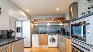 A modern kitchen with a dishwasher, washing machine, microwave, and coffee maker. - 11 Stonegate Court -  a family break that sleeps 4 guests  in 2 bedrooms (York)