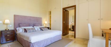 A neatly arranged bedroom with a bed, bedside tables, a chair, and a wardrobe.